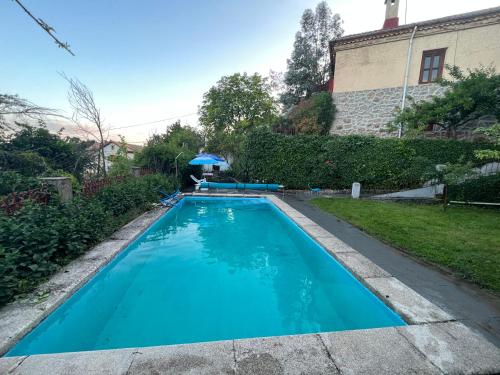 une grande piscine bleue en face d'une maison dans l'établissement Casa independiente 4 habitaciones, à Miraflores de la Sierra