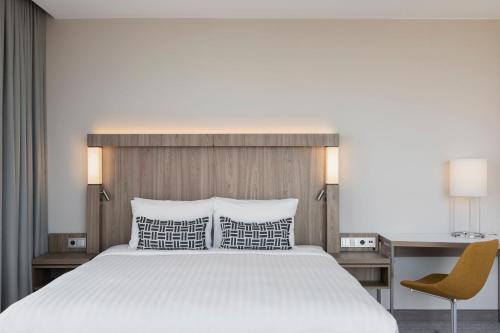 a bedroom with a bed and a desk and a chair at Courtyard by Marriott Szczecin City in Szczecin