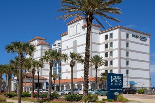 um grande edifício branco com palmeiras em frente em Four Points by Sheraton Jacksonville Beachfront em Jacksonville Beach