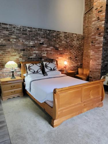 um quarto com uma cama de madeira e uma parede de tijolos em Olde Foundry Apt em Pictou