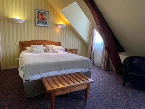 a bedroom with a large bed and a chair at Logis Hôtel de la Tête Noire in Autun