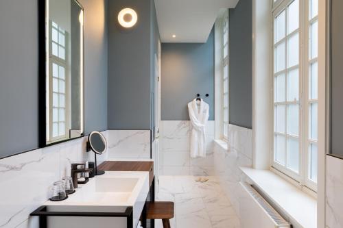La salle de bains est pourvue d'un lavabo et d'un miroir. dans l'établissement Sapphire House Antwerp, Autograph Collection, à Anvers