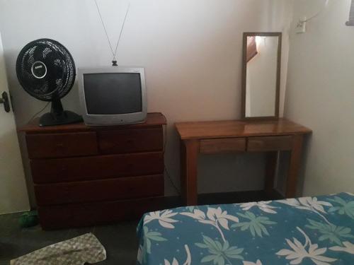 a bedroom with a tv on a dresser and a mirror at AP DA FABY in Barra de São Miguel