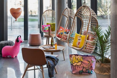 a living room with chairs and a table and a rattan basket chair at Moxy Szczecin City in Szczecin
