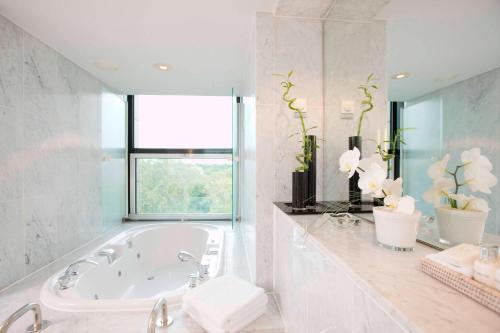 a white bathroom with a tub and a window at Sheraton Berlin Grand Hotel Esplanade in Berlin