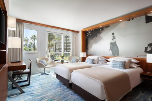 two beds in a hotel room with a painting on the wall at JW Marriott Cannes in Cannes
