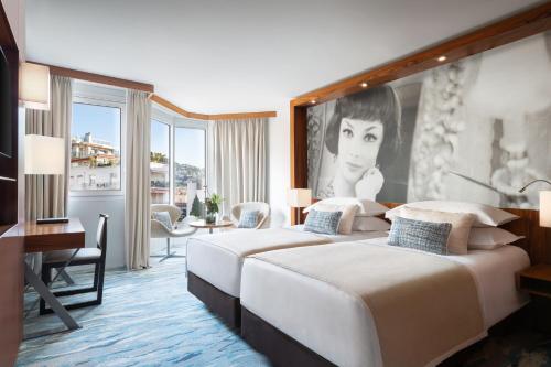 a hotel room with two beds and a painting of a woman at JW Marriott Cannes in Cannes