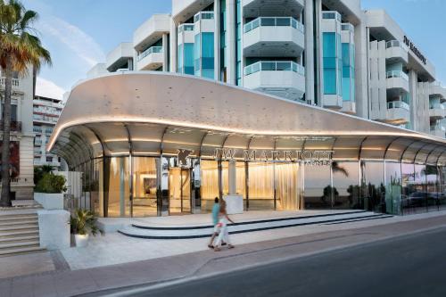 a woman walking past a building with a large building at JW Marriott Cannes in Cannes