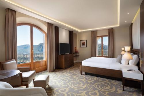 ein Hotelzimmer mit einem Bett und einem großen Fenster in der Unterkunft Renaissance Tuscany Il Ciocco Resort & Spa in Barga