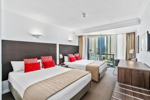 two beds in a hotel room with red pillows at Hotel Deluxe Twin at Legends - Q Stay in Gold Coast