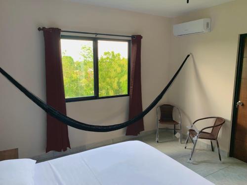 a bed with a hammock in a room with a window at Hotel Puerto Tixkokob in Tixkokob