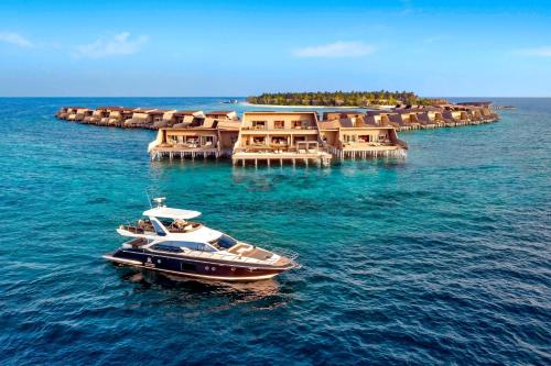 a boat in the water in front of a resort at The St. Regis Maldives Vommuli Resort in Dhaalu Atoll
