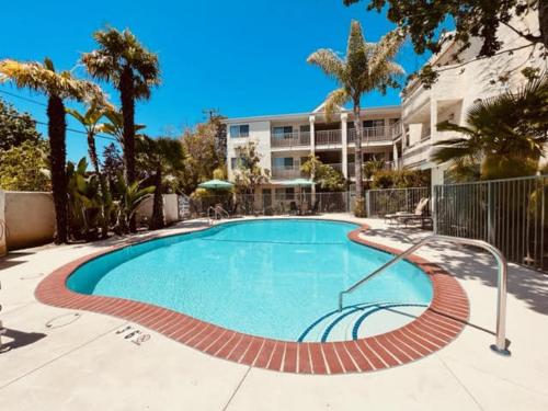 a swimming pool in front of a building with palm trees at Hotel Buena Vista - San Luis Obispo in San Luis Obispo