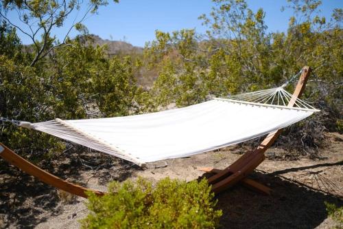 a hammock on the beach with trees in the background at The Raven House - Renovated Homestead Cabin in Joshua Tree
