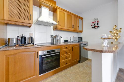 Una cocina con gabinetes de madera y encimera. en Penthouse Naomi with two terraces, private solarium, sea view, swimming pool, with underground parking, pets allowed, en Orihuela Costa