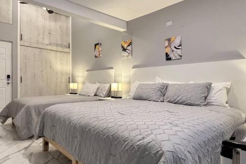 a white bedroom with two beds and two lamps at Habitación Plata #2 in Aguascalientes