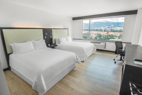 a hotel room with two beds and a large window at Four Points by Sheraton Cuenca in Cuenca