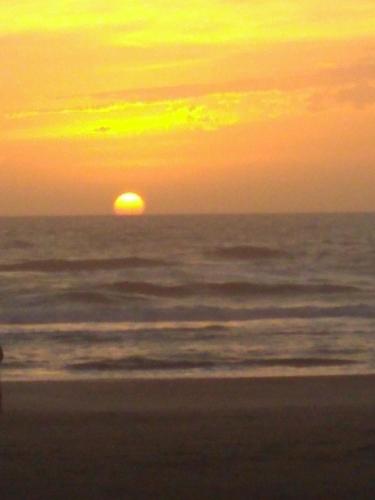una puesta de sol en la playa con el sol en la distancia en El depto de mirta 964 Esquiu en San Bernardo