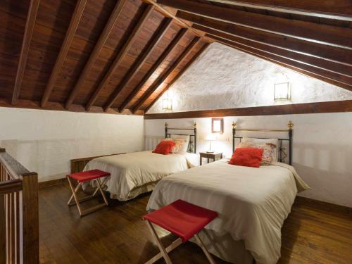 Habitación con 2 camas con sillas rojas. en Casa Rural la Montañeta en Santa Lucía