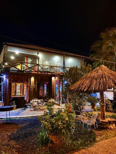 a house with a straw umbrella and tables and chairs at Hotel Village Termas de Dayman in Termas del Daymán