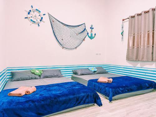 ein Schlafzimmer mit zwei Betten mit blauer Bettwäsche und einer Hängematte in der Unterkunft Phen Vas Poolvilla in Ban Nok