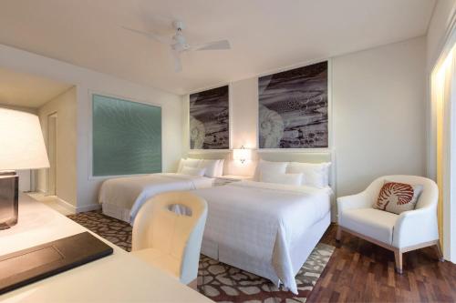 a hotel room with two beds and a chair at The Westin Langkawi Resort & Spa in Kuah