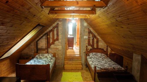 Cette chambre mansardée comprend deux lits et un couloir. dans l'établissement Vikend kuća Fruška Gora, à Velika Remeta
