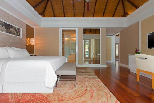 a bedroom with a white bed and a living room at The Westin Langkawi Resort & Spa in Kuah