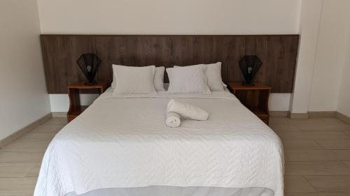 a white bed with two nightstands and two white towels on it at Lava House Hostal in Puerto Ayora