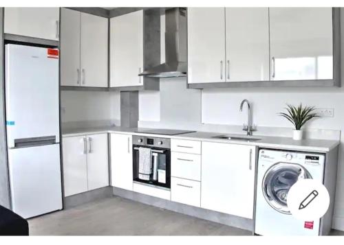 a kitchen with white cabinets and a washing machine at Flat 22, Spacious two bedroom apartment in Canvey