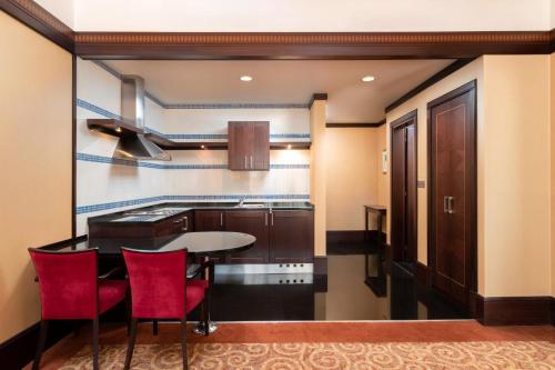 a kitchen with a table and red chairs in a room at Holiday Inn Kuwait by IHG in Kuwait