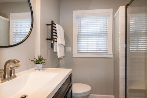 ein Badezimmer mit einem Waschbecken, einem WC und einem Spiegel in der Unterkunft Stylish & Comfy 5 Location Private Backyard Updated Close to Downtown Walkable in Raleigh