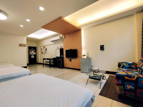 ein Hotelzimmer mit einem Bett, einem Sofa und einem TV in der Unterkunft Huadong Homestay in Taitung