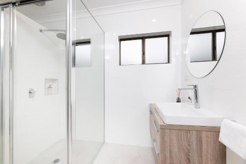 a bathroom with a shower and a sink and a mirror at 23 Elouera Crescent in Forster