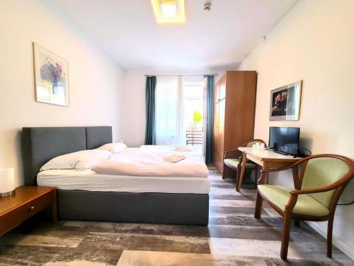 a bedroom with a bed and a desk with a computer at City Center Hotel Garni Cuxhaven in Cuxhaven