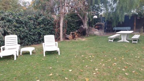tres sillas blancas y una mesa en un patio en Cabaña los Aromos en Maipú