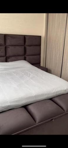 a bed with white sheets and a brown head board at Appartement Nador Jadid in Nador
