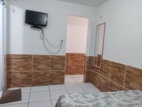 um quarto com uma cama e uma televisão na parede em Pousada Carimbó em Fortaleza