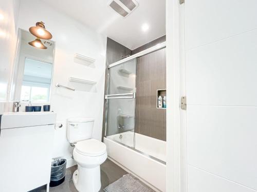 a white bathroom with a toilet and a shower at Spacious 4BR Townhouse in Mid City - WH-C2 in Los Angeles