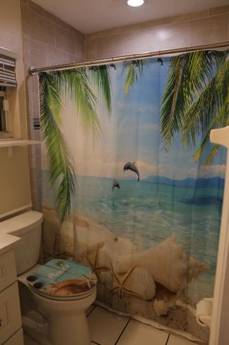 a bathroom with a toilet with a tropical shower curtain at 3-bedroom home between the beach & theme parks in Deltona