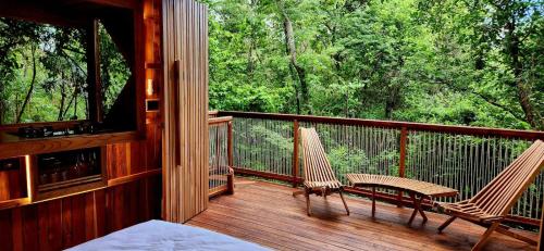 a porch with two chairs and a bench on it at Tamarindo Pura Selva Eco Tree House in Guatemala