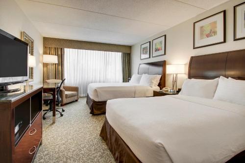 a hotel room with two beds and a flat screen tv at Holiday Inn Westbury-Long Island by IHG in Carle Place