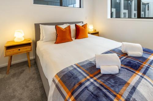 ein Schlafzimmer mit einem großen weißen Bett mit orangefarbenen Kissen in der Unterkunft Cashel Street Hideaway 2 bed 2 bath in Christchurch