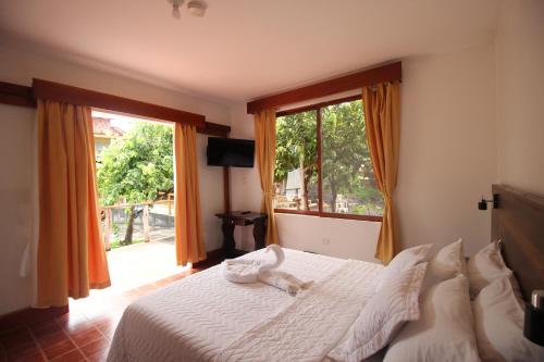 a bedroom with a bed with white sheets and a window at Lava House Hostal in Puerto Ayora