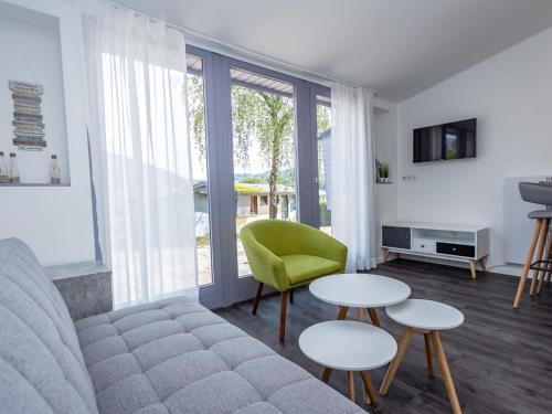 a living room with a couch and two tables and a green chair at Hillside Haven in Waxweiler in Waxweiler