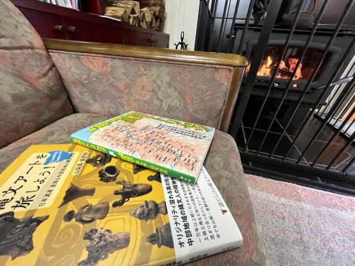 a book sitting on top of a chair next to a fireplace at Guest Room Furusatomura Kogeikan in Omachi