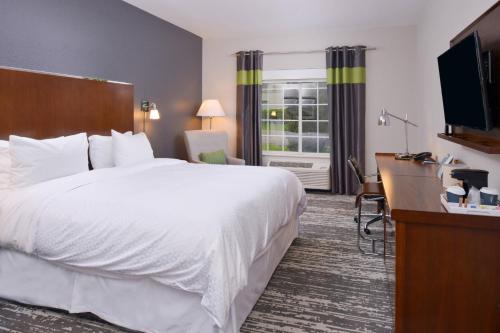 a hotel room with a large white bed and a desk at Four Points By Sheraton Mount Prospect O’Hare in Mount Prospect