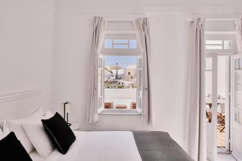 a white bedroom with a bed and a window at Vedema, a Luxury Collection Resort, Santorini in Megalokhori