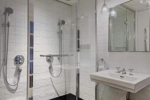 a white bathroom with a shower and a sink at Kaya Great Northern Hotel, London in London