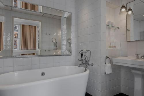 Baño blanco con bañera y lavamanos en Great Northern Hotel, A Tribute Portfolio Hotel, London en Londres